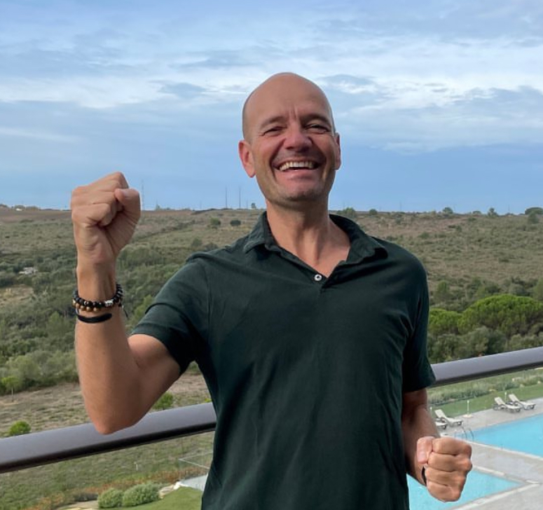 portrait d'un homme souriant poings serrés en signe de victoire sur terrasse avec piscine, photo lifestyle d'une campagne brand content réalisée par south management