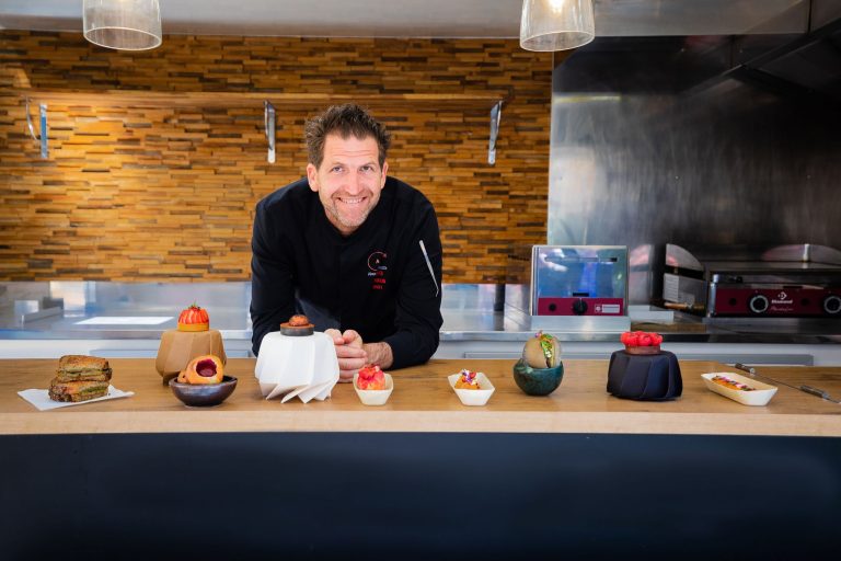 portrait du chef alexandre mazzia souriant en cuisine devant ses desserts presentes