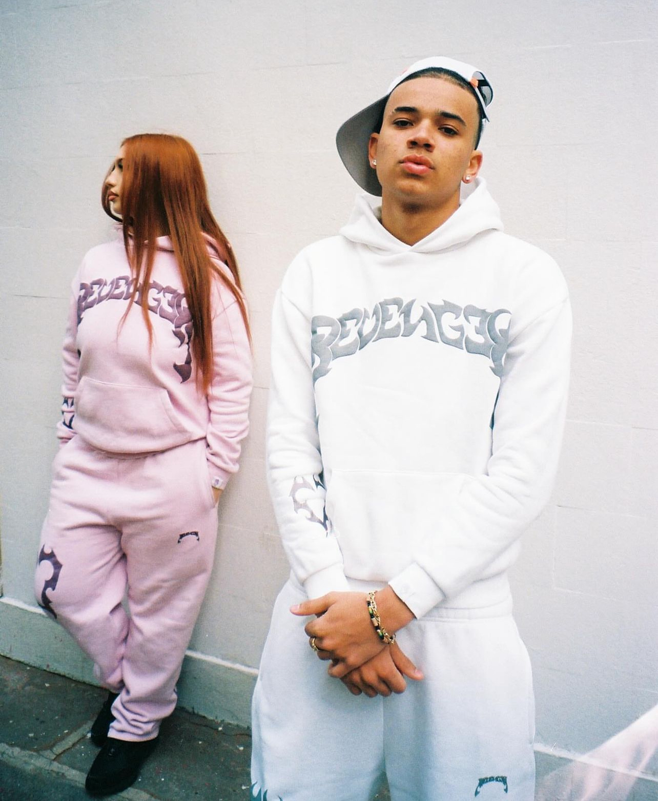 duo d influenceurs en sweat blanc et rose pose contre un mur pour shooting streetwear